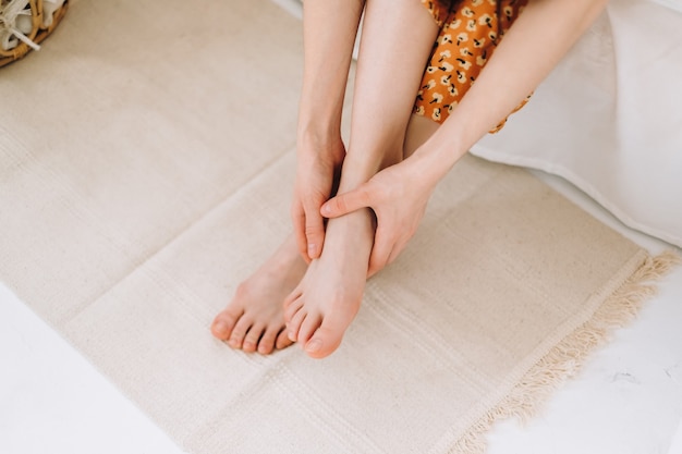 Vrouw zittend op het bed en masseert haar voet