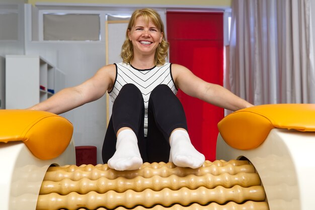 Vrouw zittend op het massagegereedschap voor de benen met een grote vreugde op haar gezicht