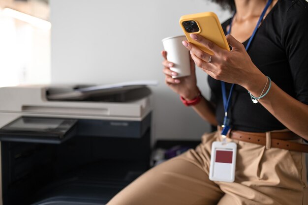 Vrouw zittend op kantoor met een telefoon en kopje koffie in handen