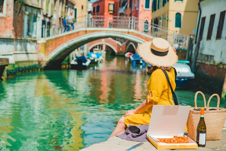 Vrouw zittend op pier kijkend naar gandola's in Venetië Canal