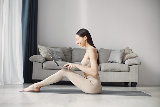 Foto vrouw zittend op yoga man in leggins en top tijdens het gebruik op laptop thuis