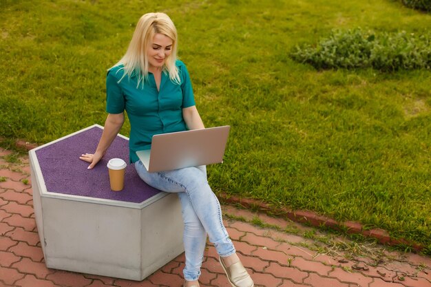 vrouw zoekt baan met een laptop in een stadspark in de zomer