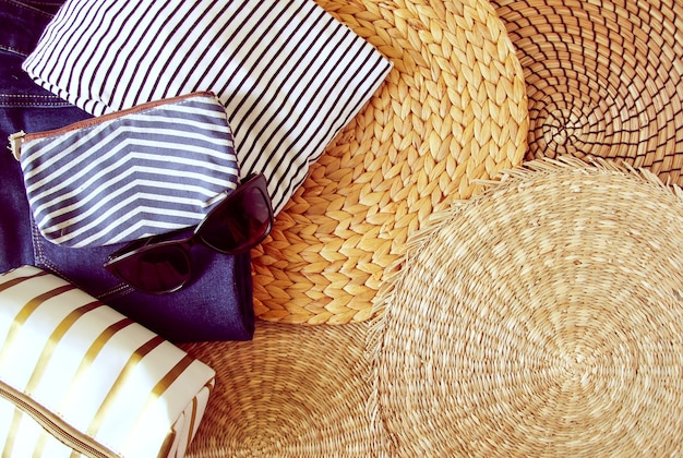 Vrouw zomer kleding en accessoires op rieten placemat achtergrond, bovenaanzicht.