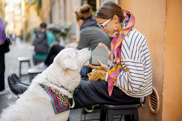 Vrouw zorgt voor haar hond terwijl ze pasta eet in het openluchtcafé