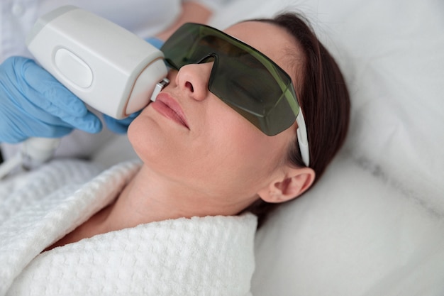 Vrouw zorgt voor haar huid en doet cosmetologie en laserprocedures