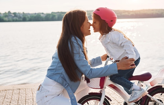 Vrouw zorgt voor haar kleine meisje Moeder met haar jonge dochter is samen met de fiets buiten