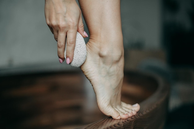 Vrouw zorgt voor hakken in de badkamer met puimsteen