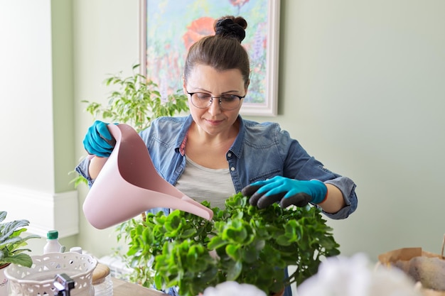 Vrouw zorgt voor kamerplanten hobby's en vrije tijd natuur in huis