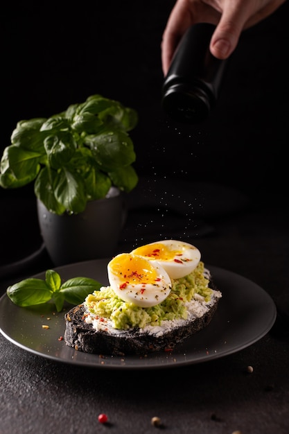 Vrouw zout een sandwich met avocado en eieren