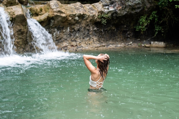 Vrouw zwemmen in de bergrivier met een waterval