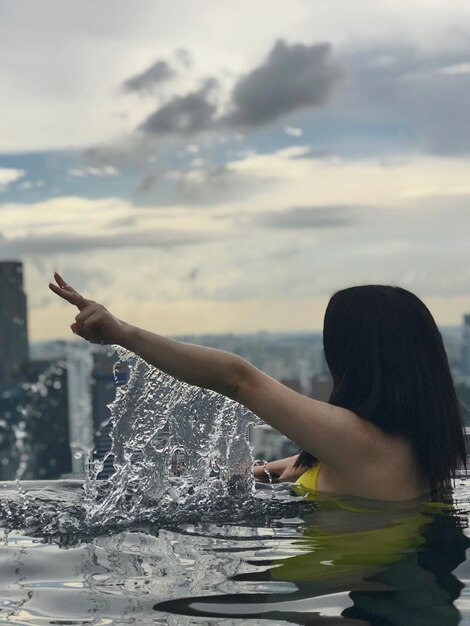 Foto vrouw zwemt in een infinity zwembad tegen de lucht