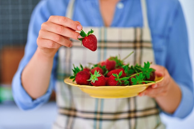 Vrouwelijk bord met verse rijpe biologische aardbeien in de keuken thuis