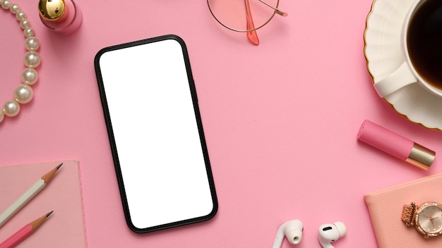 Vrouwelijk bureau met smartphone wit scherm mockup op roze achtergrond bovenaanzicht