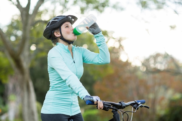 Vrouwelijk fietser drinkwater in bos