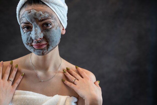 Vrouwelijk gezicht met cosmetica die grijs bubbelmasker op zwarte achtergrond reinigen Anti-aging behandeling huidverzorging