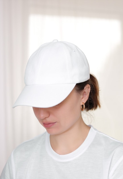 Vrouwelijk model draagt een witte baseballcap. Witte dop mockup, sjabloon voor afbeelding, tekst of logo. Meisje met vizier van pet. Vrije ruimte, kopieer ruimte.