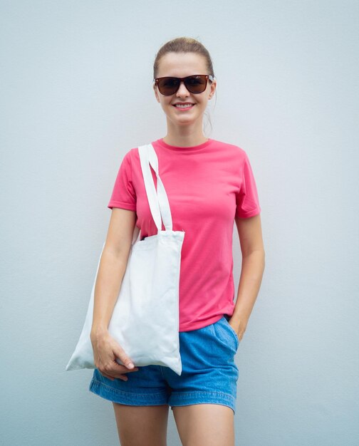 Vrouwelijk model met roze blanco t-shirt op de achtergrond van een grijze muur