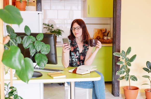 Vrouwelijk Model thuiskantoor dat haar computer met behulp van en koffie drinkt