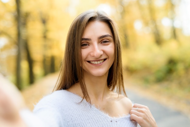 Vrouwelijk portret. Jonge vrouw in vrijetijdskleding poseren in herfstbos met gele bladeren