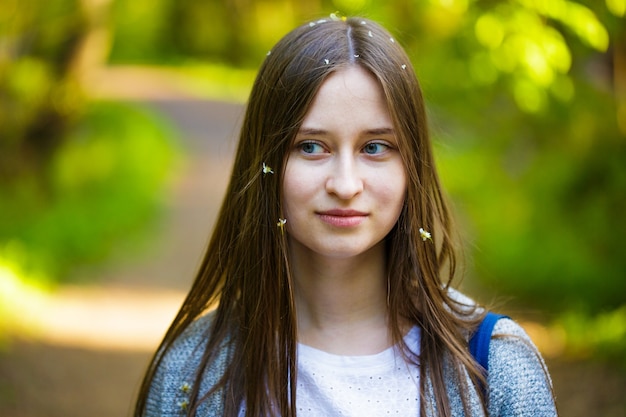 Vrouwelijk portret van een jonge vrouw met een blanke uitstraling stit in het park op een pad in een lentedag