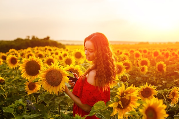 Vrouwelijk portret van jonge vrouw op gebied van bloeiende zonnebloemen in stralen van zonsondergang schattig meisje van cauca...