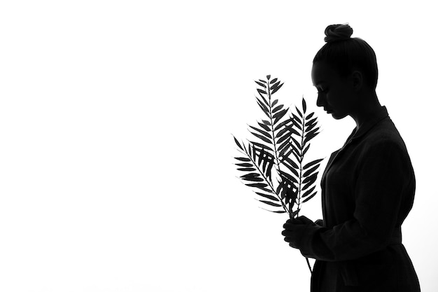 Vrouwelijk silhouet met groene bladeren zijaanzicht schaduw terug verlichte witte achtergrond young