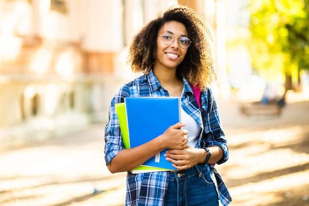 Vrouwelijke Afrikaanse student met een boek in een universiteitspark