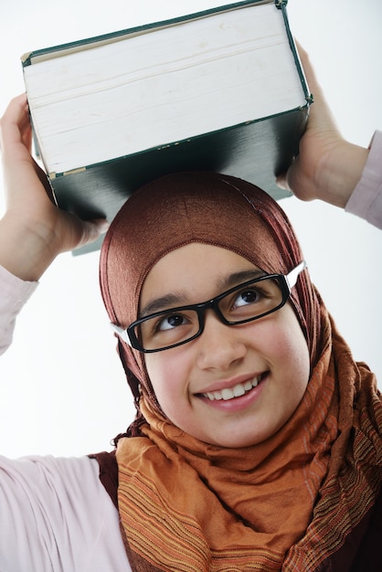Foto vrouwelijke arabische student die groot boek op hoofd in evenwicht brengt