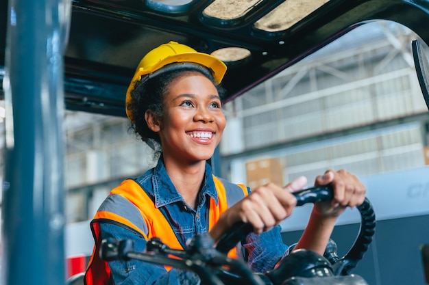 Vrouwelijke arbeider bij vorkheftruckchauffeur, gelukkige glimlach, geniet van het werken in het logistieke verzendmagazijn van de industriële fabriek
