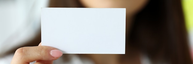 Vrouwelijke arm in pak geven blanco visitekaartje aan bezoeker