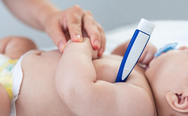 Vrouwelijke arts die de peuter van de babyjongen onderzoekt met behulp van een thermometer voor koortsgriep