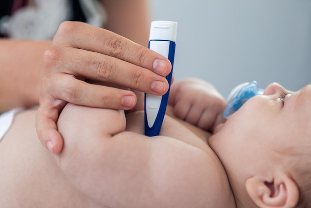 Vrouwelijke arts die de peuter van de babyjongen onderzoekt met behulp van een thermometer voor koortsgriep