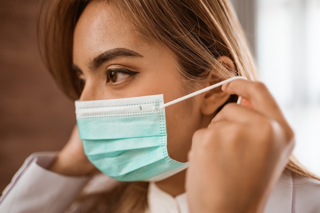 Vrouwelijke arts die een medisch masker draagt en naar de camera kijkt