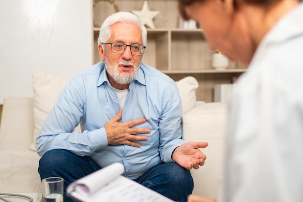 Vrouwelijke arts die een oudere oudere man onderzoekt in het kantoor van de arts of thuis oude man patiënt en dokter hebben