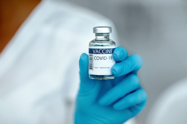 Vrouwelijke arts die het COVID-19-vaccin in de hand houdt. Gezondheidszorg en medisch concept. COVID-19-vaccin in handen van de onderzoeker, concept van corona-virusbehandeling,