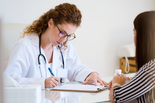 Foto vrouwelijke arts die medicijn voor patiënt op het kantoor voorschrijven.