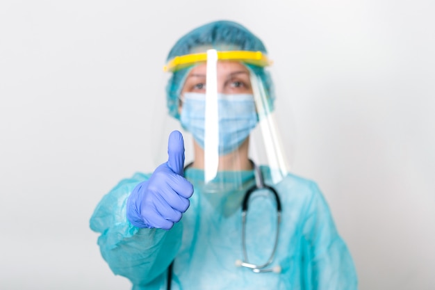 Vrouwelijke arts die PPE-beschermingssuite draagt om te vechten en de verspreiding van Covid-19 en covid-19-uitbraak te stoppen met duimen omhoog