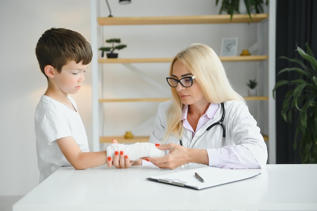 Vrouwelijke arts en jonge jongen met een gebroken arm