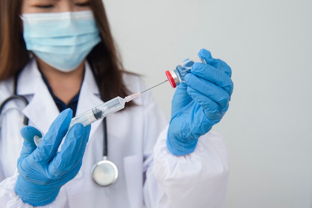 Vrouwelijke arts houdt spuit en fles met vaccin vast voor genezing van coronavirus