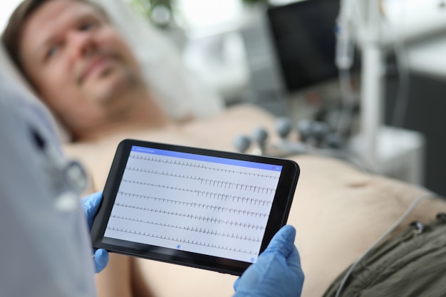 Vrouwelijke arts houdt tablet met elektrocardiogram