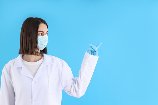 Vrouwelijke arts in masker en handschoenen op blauwe achtergrond