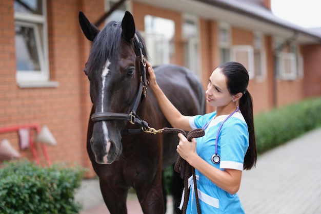 Vrouwelijke arts in uniform met paard in stal