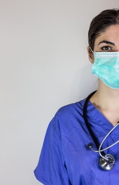Foto vrouwelijke arts in werkende pyjama met masker voor adembescherming tegen coronavirus.