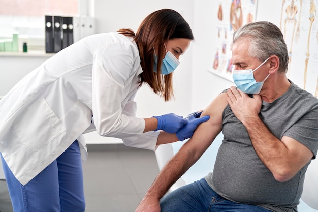 Vrouwelijke arts injecteert een spuit aan een patiënt