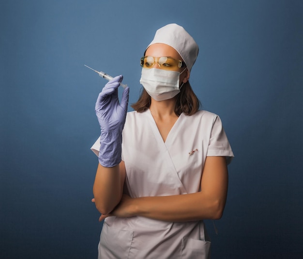 Vrouwelijke arts met een medisch masker houdt een spuit in haar handen. vaccinatie concept.