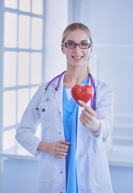 Vrouwelijke arts met een stethoscoop die hart vasthoudt.