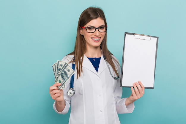 Vrouwelijke arts met fan van geld en klembord