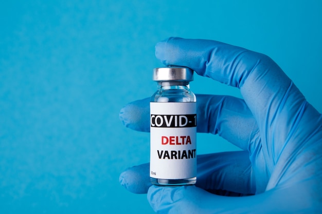 Foto vrouwelijke arts met spuit en covid-19 delta variant vaccin geïsoleerd op blauwe achtergrond. gezondheidszorg en medisch concept.