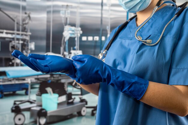 Vrouwelijke arts of verpleegster in blauw jasuniform trekt rubberen blauwe handschoenen aan en bereidt onderzoekspatiënt voor