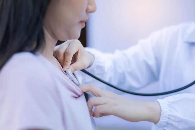 Vrouwelijke arts onderzoekt vrouw met stethoscoop op tekenen van coronavirus-longontsteking die borst van vrouw controleren in veldhospitaal.